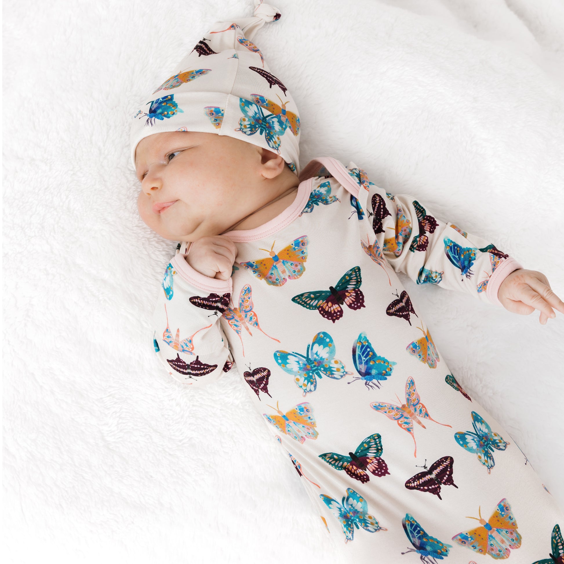 Snugly newborn baby wearing the soft Wings of Paradise butterfly print bamboo gown and hat.