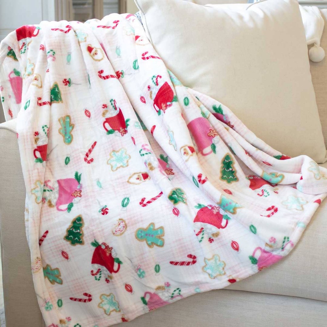 christmas blanket thats light pink with christmas cookies and cups of cocoa on it