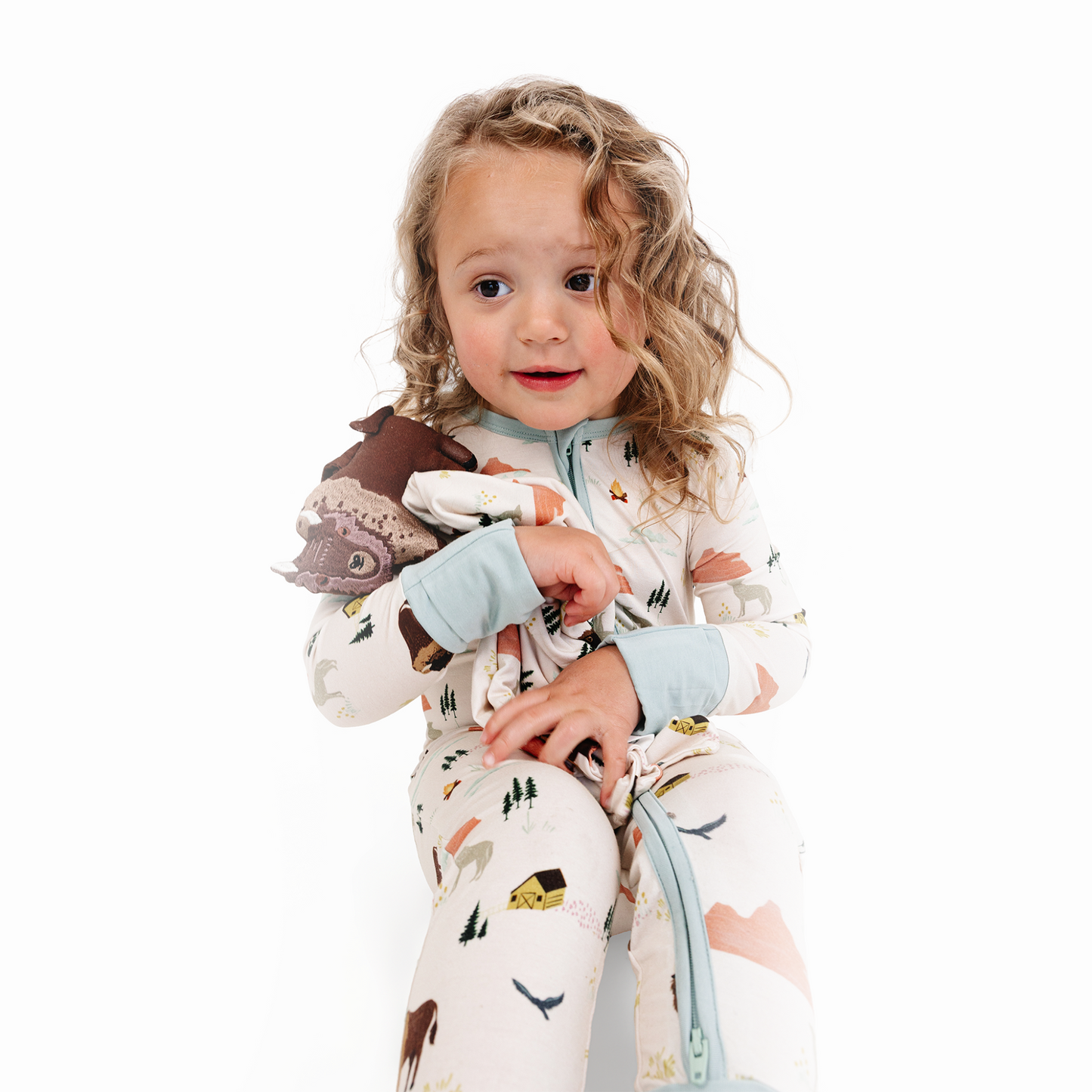 Child wearing a patterned onesie with animal designs on a white background