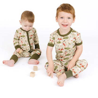 Two children wearing matching pajamas with a nature-themed design on a white background