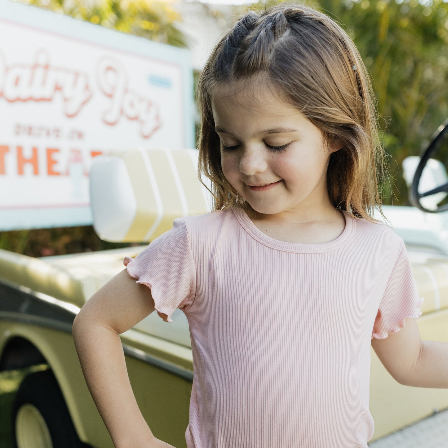 Young girl in a pink shirt standing in front of a vintage truck with 'Dixie Boy' branding.
