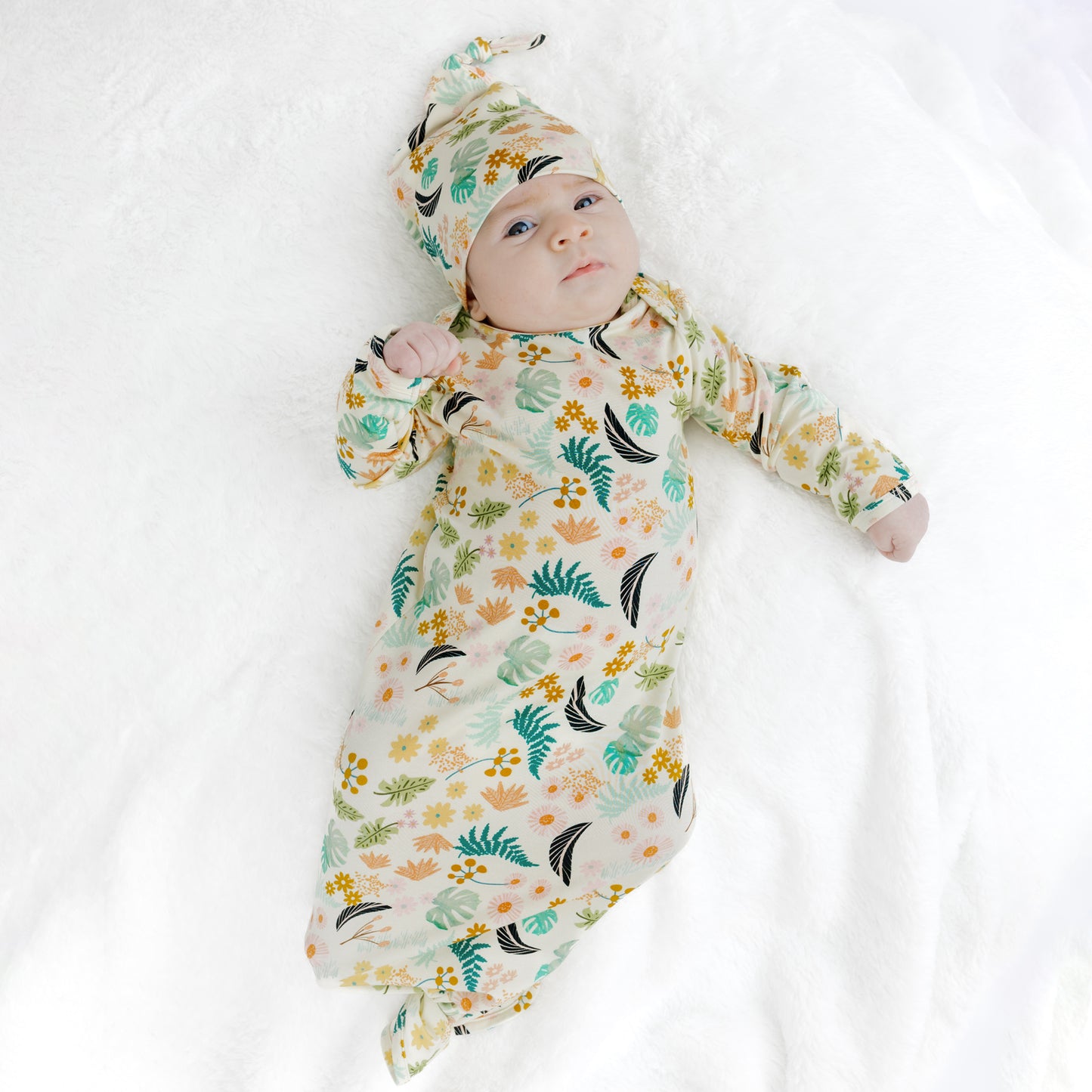 Baby girl modeling the Tropical Blooms bamboo newborn gown, an easy-to-use and comfortable outfit for new moms.