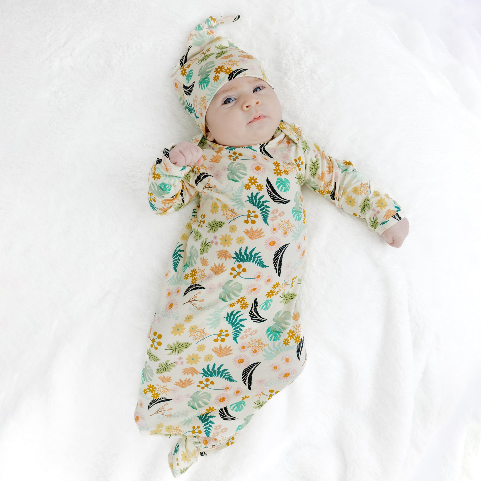 Baby girl modeling the Tropical Blooms bamboo newborn gown, an easy-to-use and comfortable outfit for new moms.