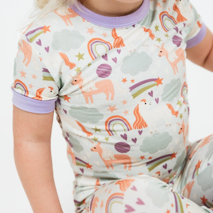 Detailed picture of our Magical Unicorn printed bamboo pajama. The print includes unicorns, rainbows, clouds, planets, stars, and hearts. The colors are purple, pink, and blu, with hints of green. 