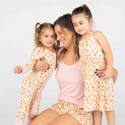 Woman with 2 girls wearing our Sandy Seashell collection. She is wearing our bubblegum tank top and our sandy shell bamboo pajama shorts. The other 2 girls are wearing the dress and our covertible bamboo pajama. 