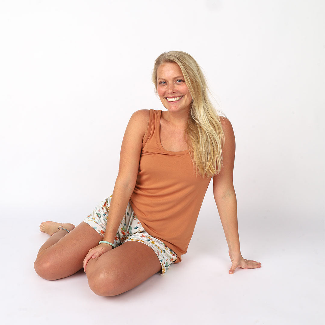 girl sits on the floor in her coral women's tank top. 