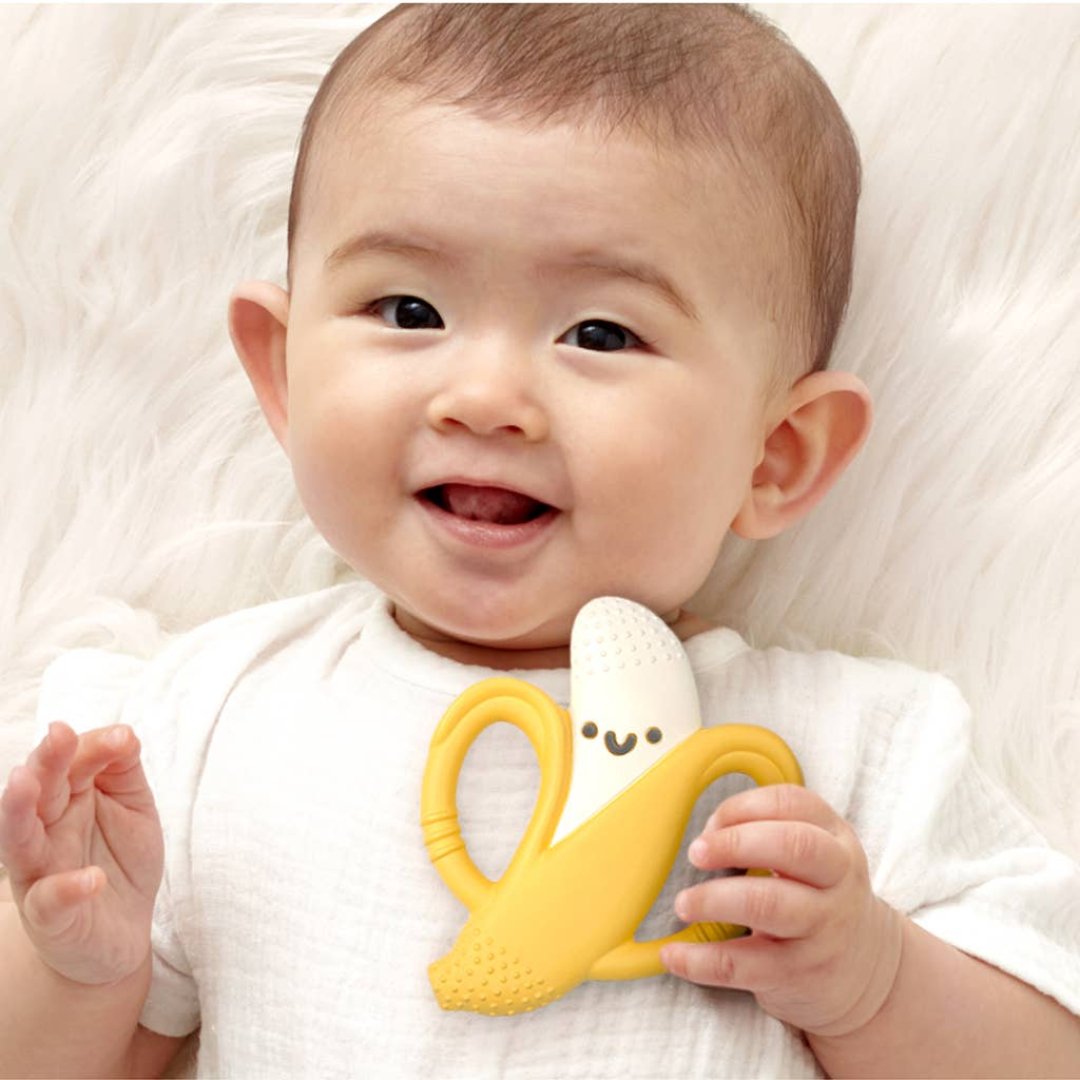 little baby holding a teether that looks like a banana