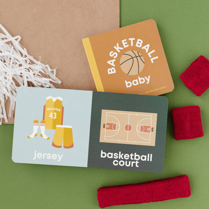 Children's books with basketball-themed illustrations on a green surface with basketball-related items.