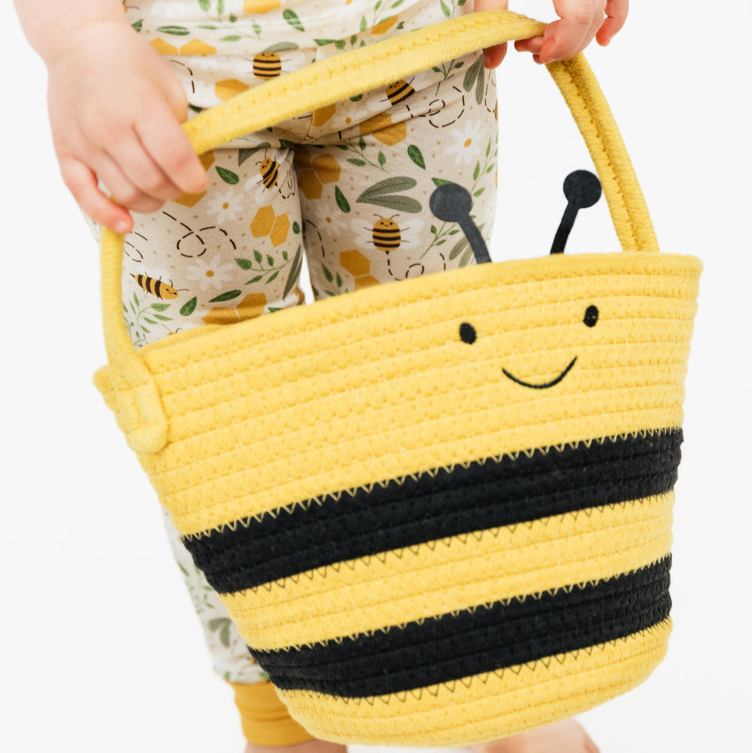 A close-up of a toddler holding a soft, hypoallergenic bee-themed rope basket, perfect for Easter and everyday use