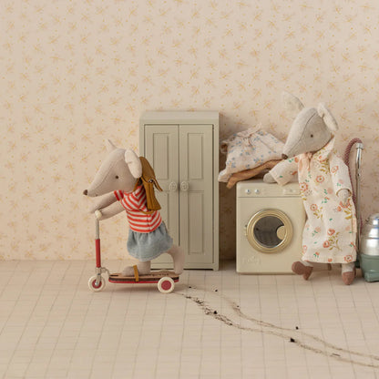 Two toy mice in a room with a washing machine and wardrobe.