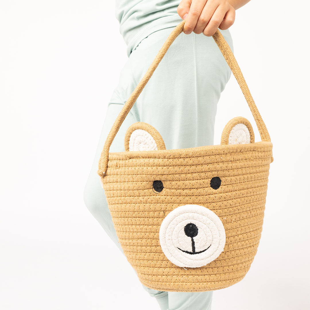 a toddler holds the bear rope basket. 