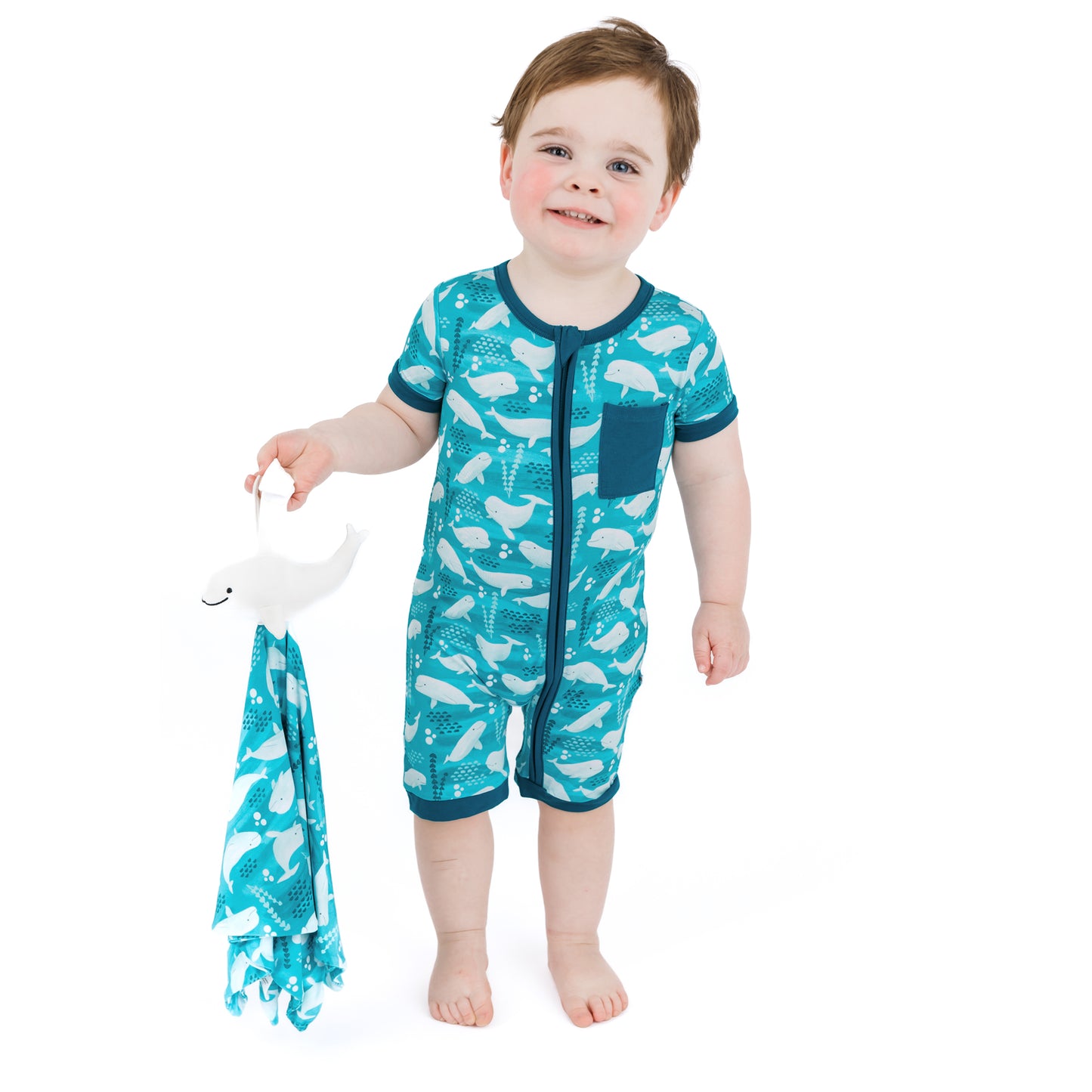 Child wearing a teal onesie with whale pattern holding a matching towel on a white background