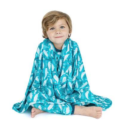 Child wrapped in a teal blanket with white patterns on a white background