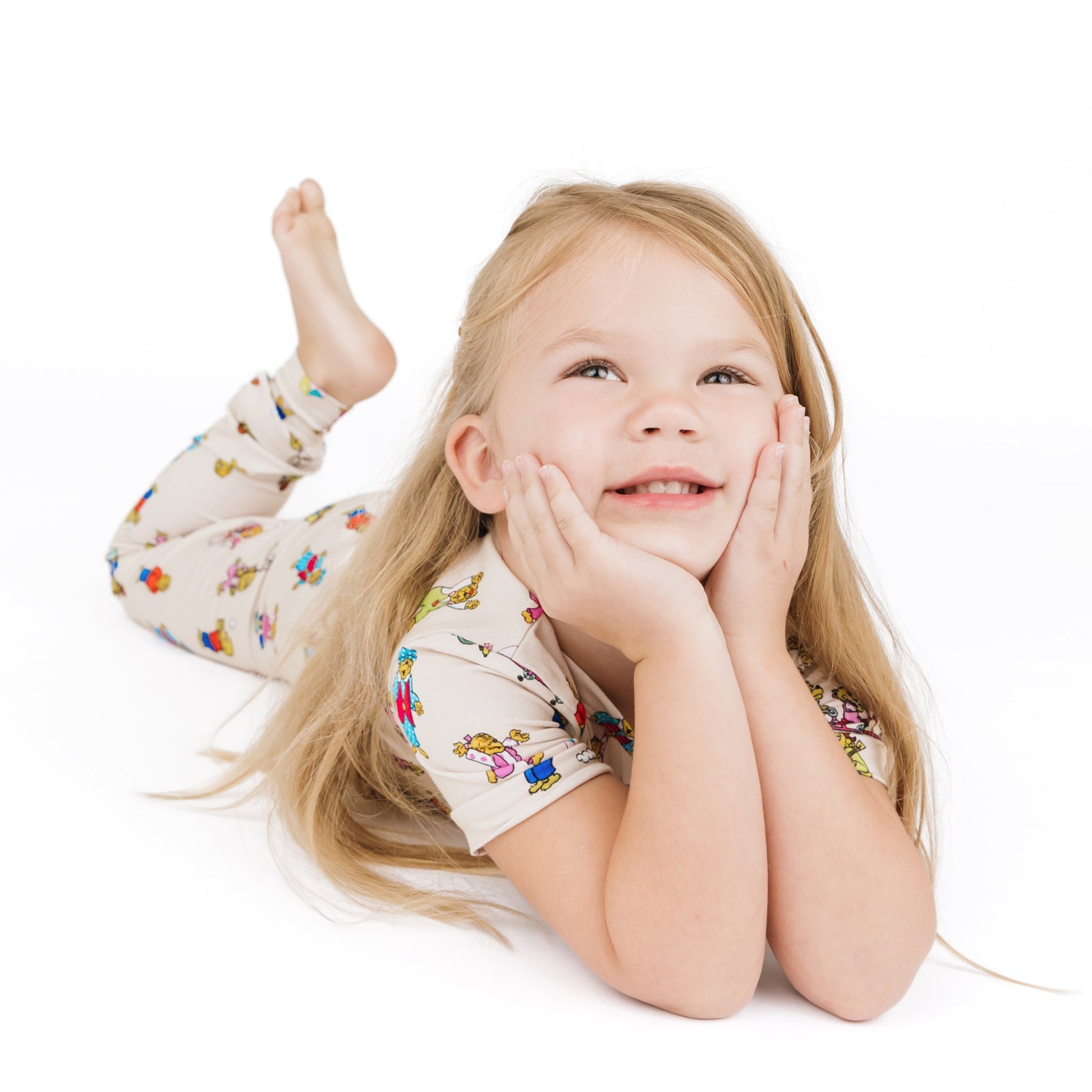 Young girl with blonde hair wearing a colorful shirt on a white background