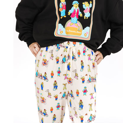 Person wearing a black hoodie with a colorful graphic and white pants with a bear pattern on a white background