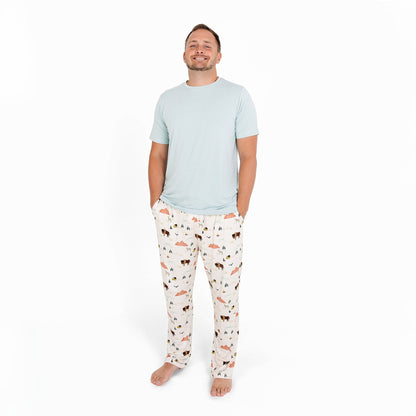 Man wearing a light blue t-shirt and patterned pajama pants on a white background