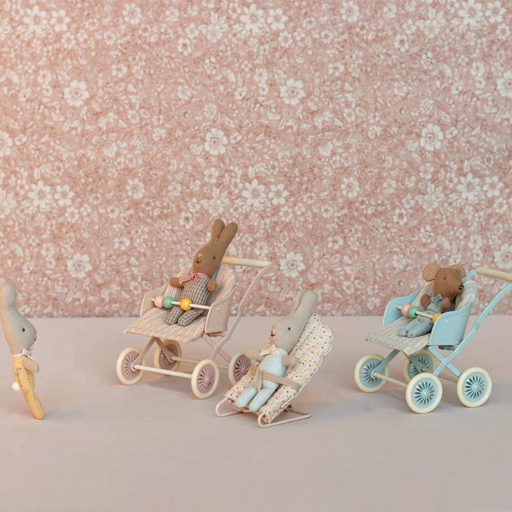 Wooden toy figures of bunnies with strollers on a floral background