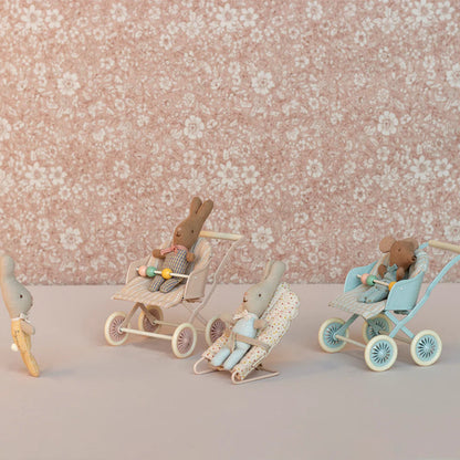 Wooden toy figures of bunnies with strollers on a floral background