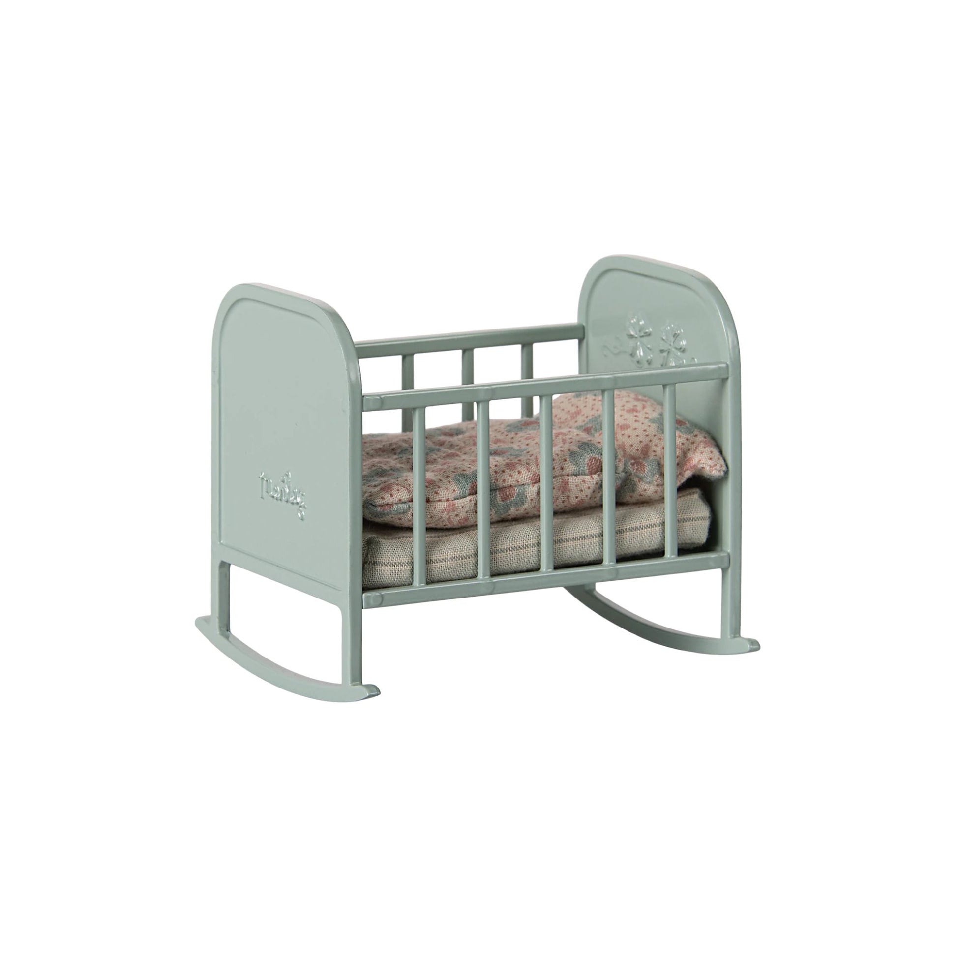 Green baby crib with a soft pink blanket on a white background