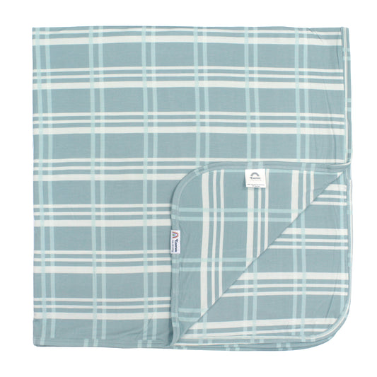 Blue and white plaid blanket with a brand label on a white background