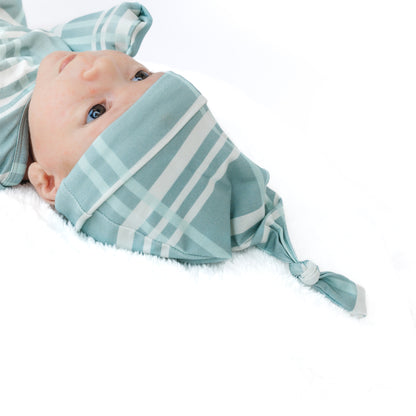 Baby wearing a light blue and white striped headscarf on a white background
