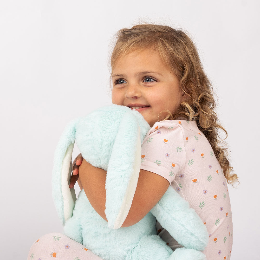 young girl hugs and squeezes the blue bunny into her chest.