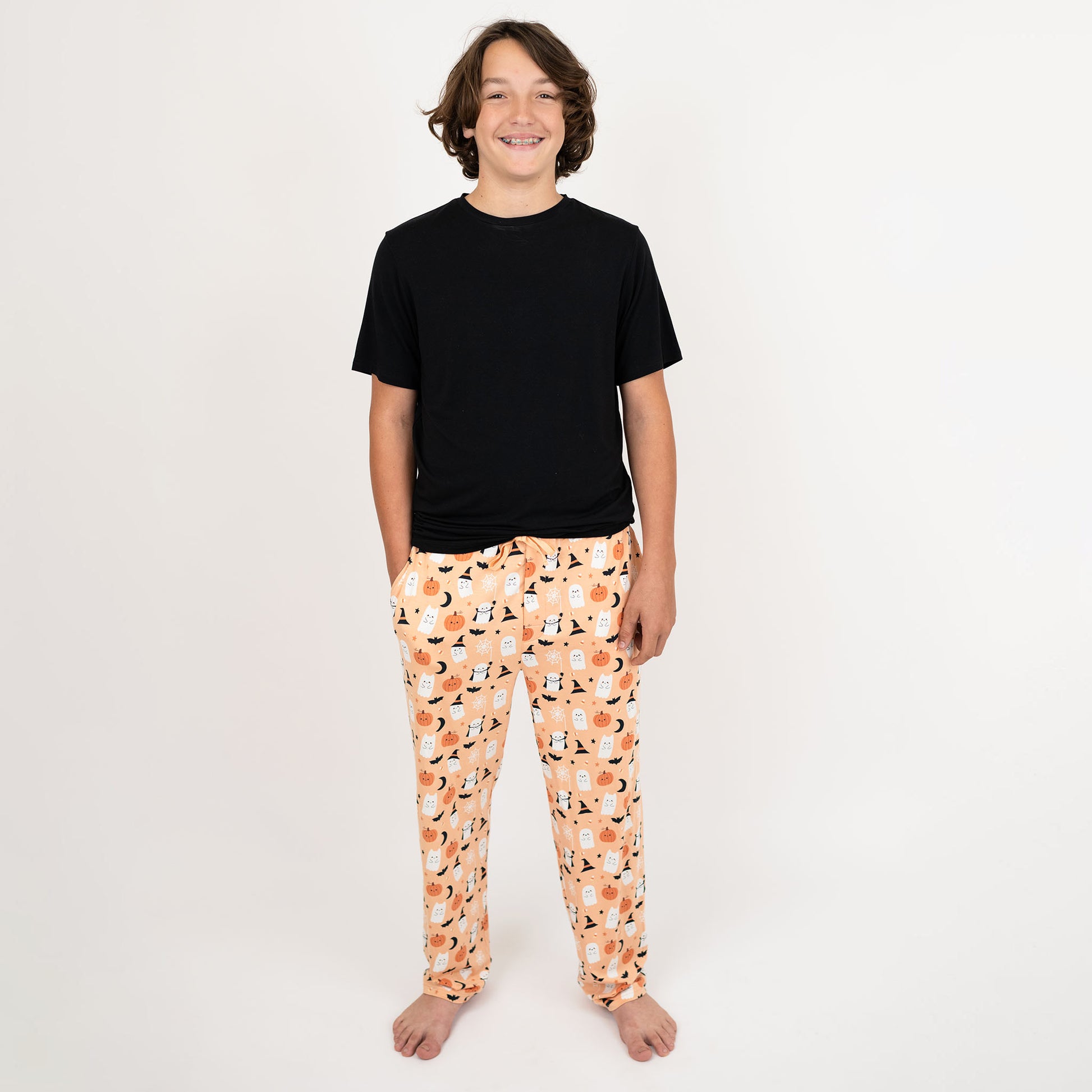 Teen wearing Boo-Tastic Halloween bamboo pajama pants, made with breathable hypoallergenic fabric in ghost and pumpkin print.