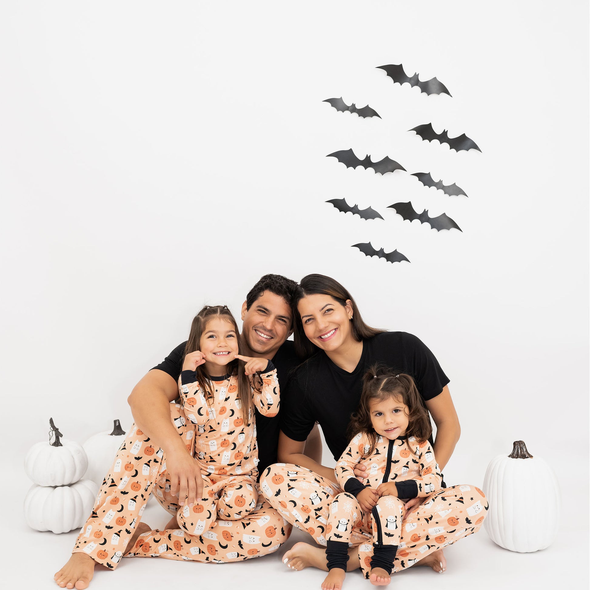 Family sitting together in Boo-Tastic Halloween bamboo pajamas, hypoallergenic and breathable, designed for cozy family matching.