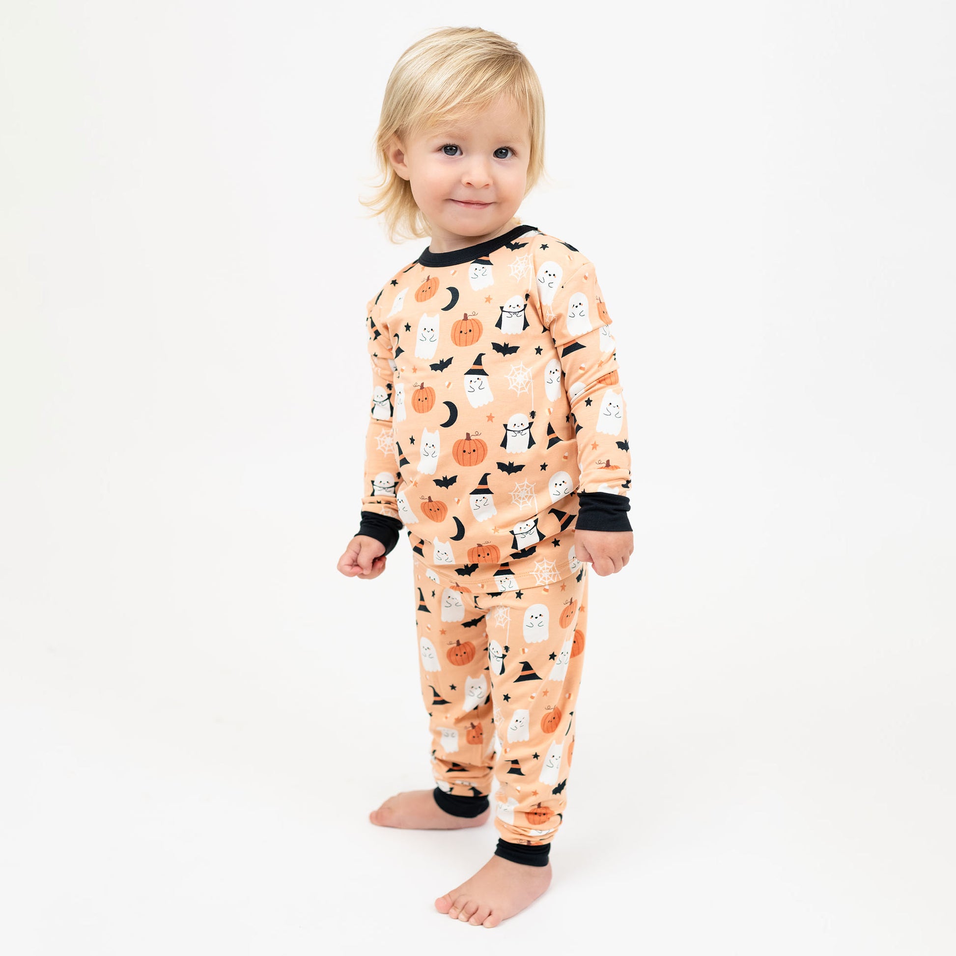 Child wearing Boo-Tastic Halloween bamboo two-piece pajamas with glow-in-the-dark ghost and pumpkin print.