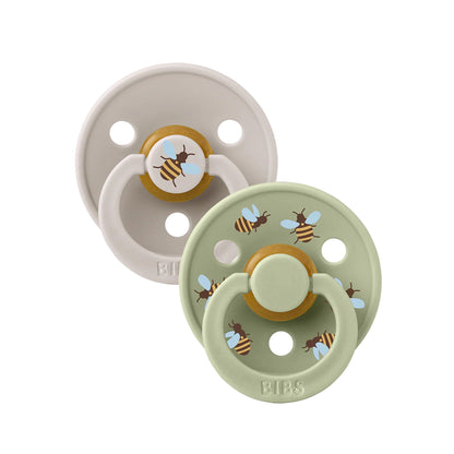 Two baby pacifiers with bee designs on a white background