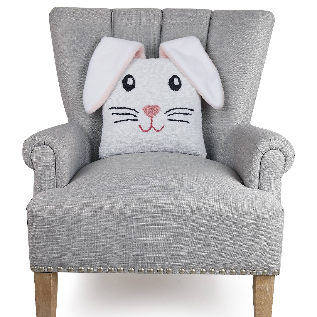 white bunny pillow that is square with floppy bunny ears that hang over the front on an oversized chair