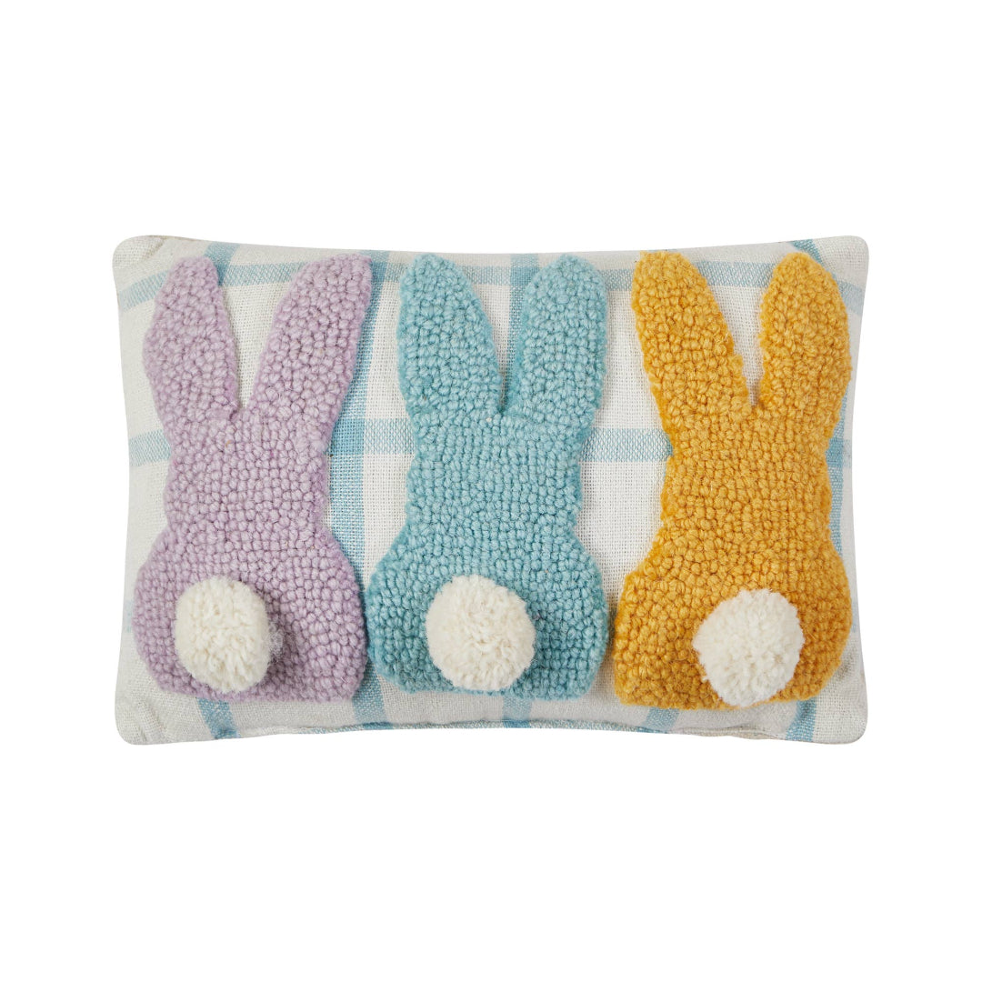 easter themed pillow thats blue and white background with 3 bunnies in purple, blue, and yellow facing away and they have fuzzy white pom pom tails