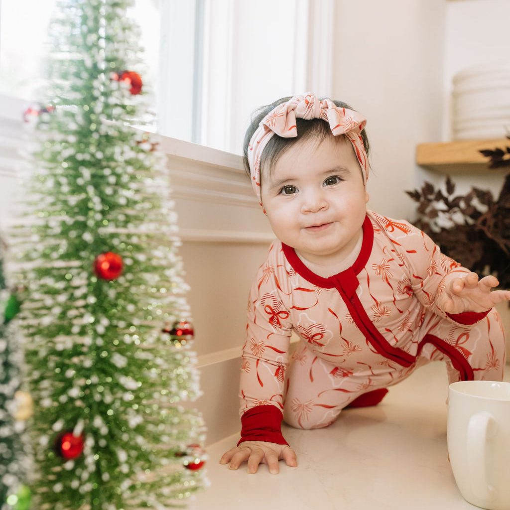 Candy Cane Coquette Bamboo Convertible Footie Romper in pink with red holiday-inspired print, red cuffs, and zipper.