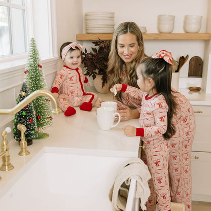 Mother and children wearing matching Candy Cane Coquette bamboo pajamas in a festive kitchen setting.