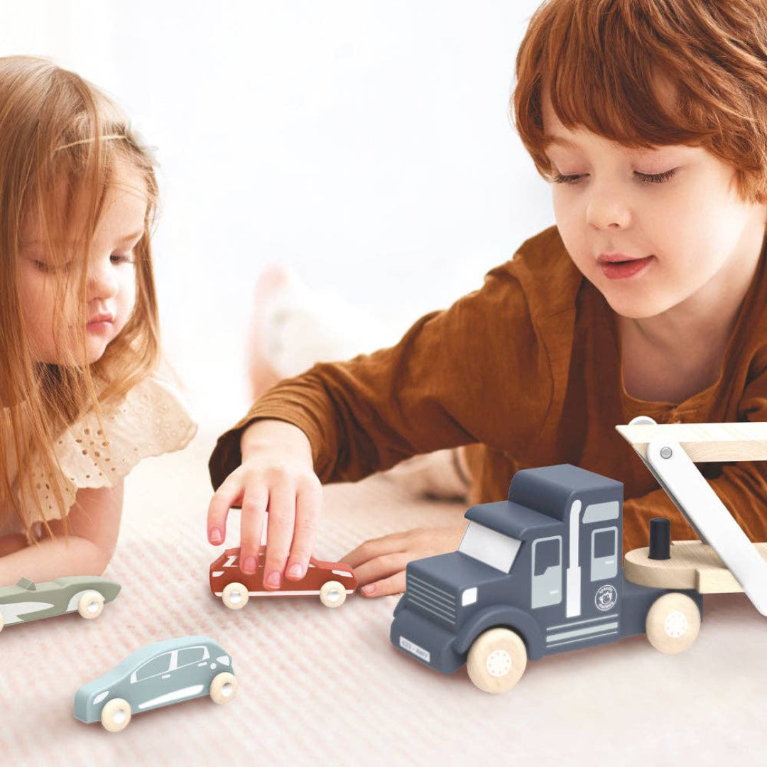 kids playing with a wooden kids toy car transporter with 4 cars in tow, including a green car, red, car, blue car, and orange car.