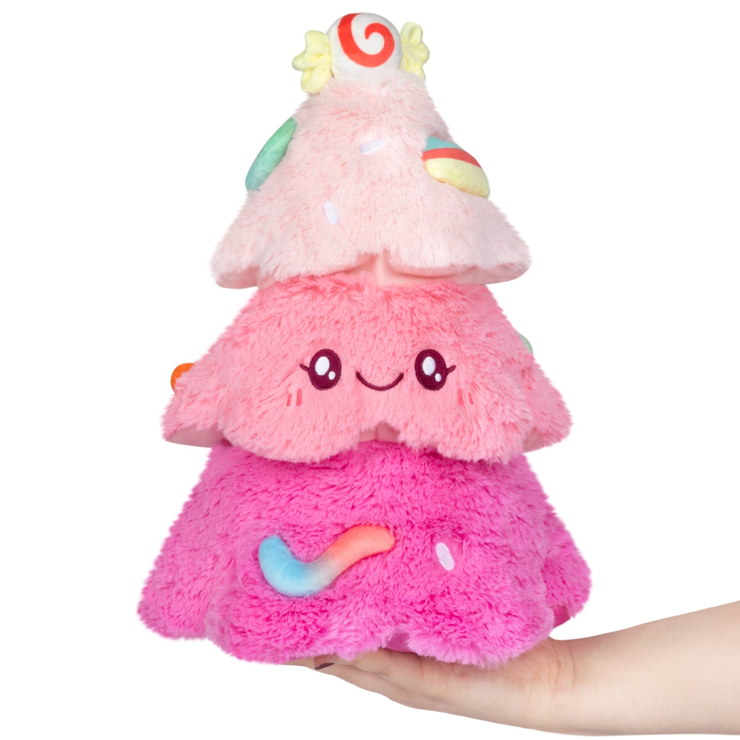 Pink plush toy resembling a tree with a hand holding it on a white background