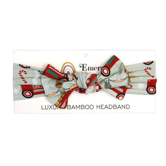 the "christmas train" baby headband. the "christmas train" pattern has various winter character that stand/ride on a red train. these characters include: santa, santa's elves, raindeers, yeti monsters, gingerbreads, reindeer, christmas trees, candy canes, presents, and snowflakes.  