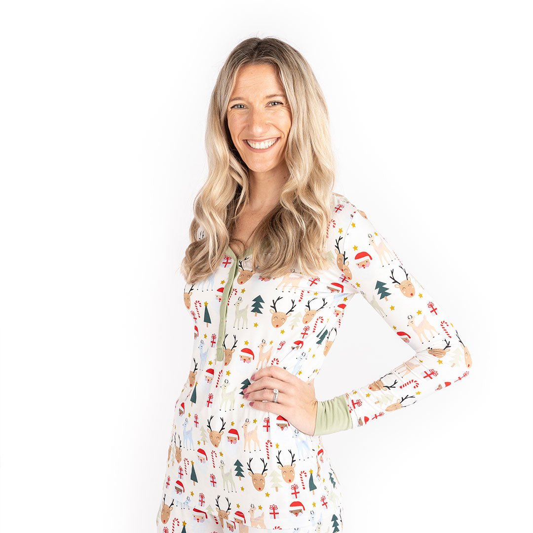 women poses with her hand on her hip. she wears the "Santa and friends" women's top. the "Santa and friends" print is a Christmas themed pattern mixed with Santa heads, candy canes, reindeer, Christmas trees, Rudolph heads, and gold stars. this is all on a white background. 