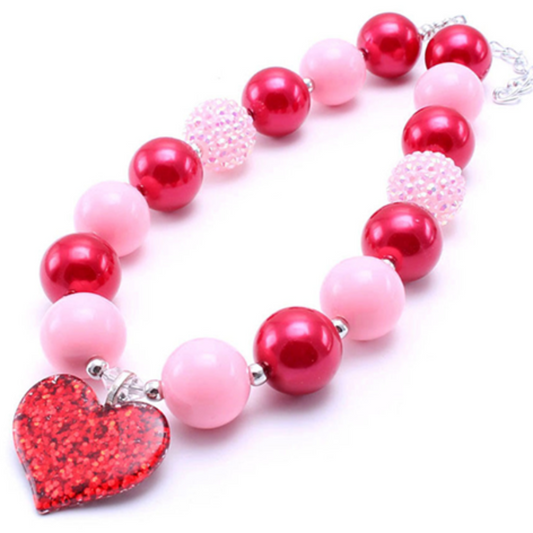 pink and red valentines day themed necklace with big round beads and a big heart charm in the middle