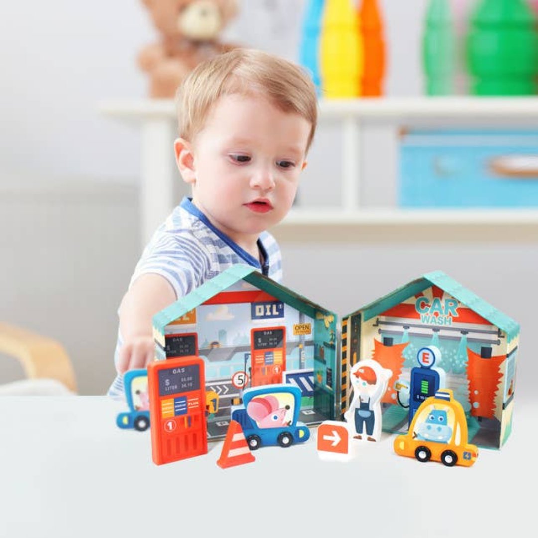 little boy playing with a toy gas station with toy cars