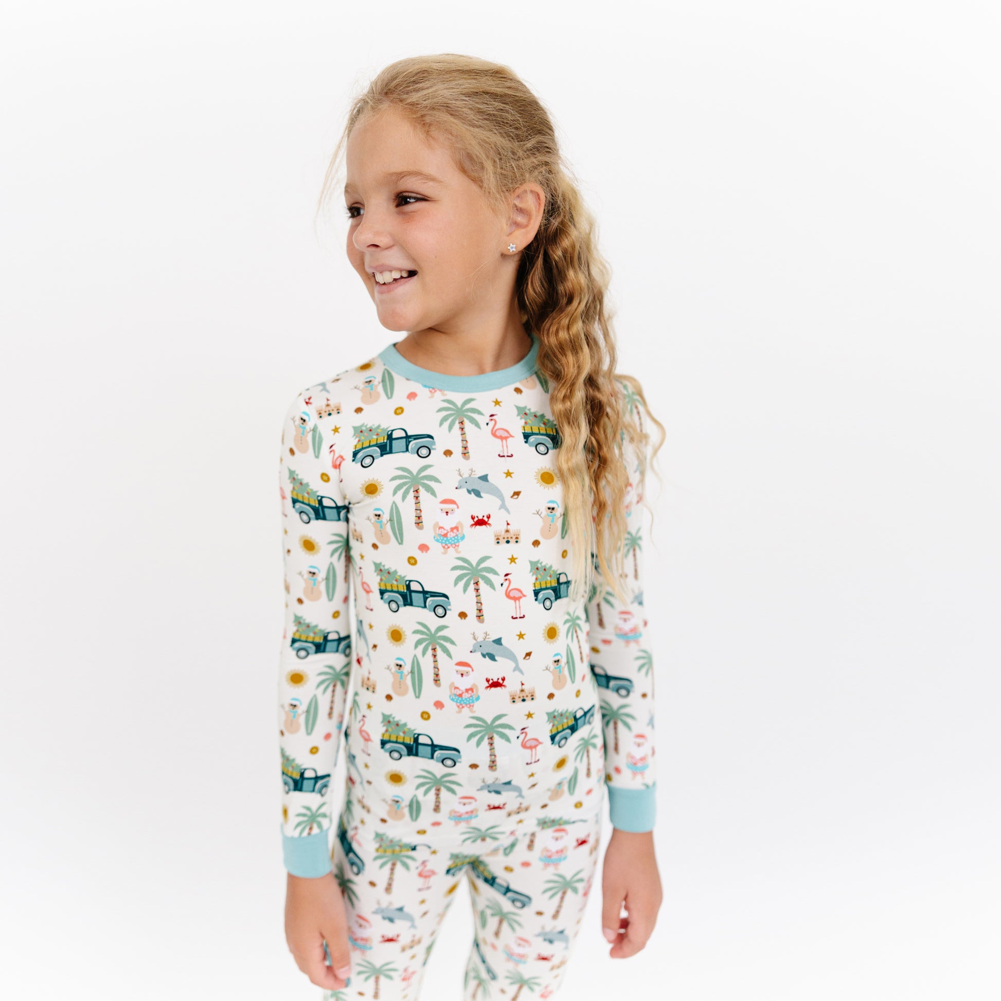 Child wearing a pajama set with vehicle and nature pattern on a white background