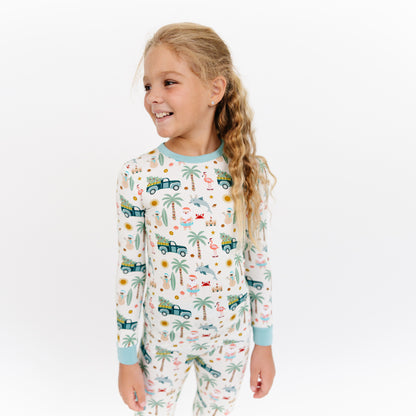 Child wearing a pajama set with vehicle and nature pattern on a white background