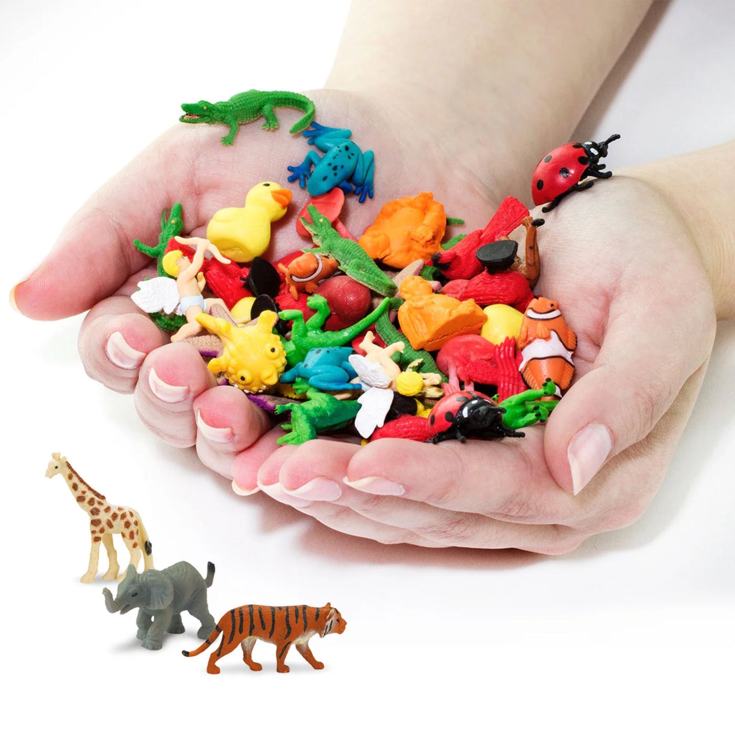 Colorful toy animals held in hands with additional animals on a white background