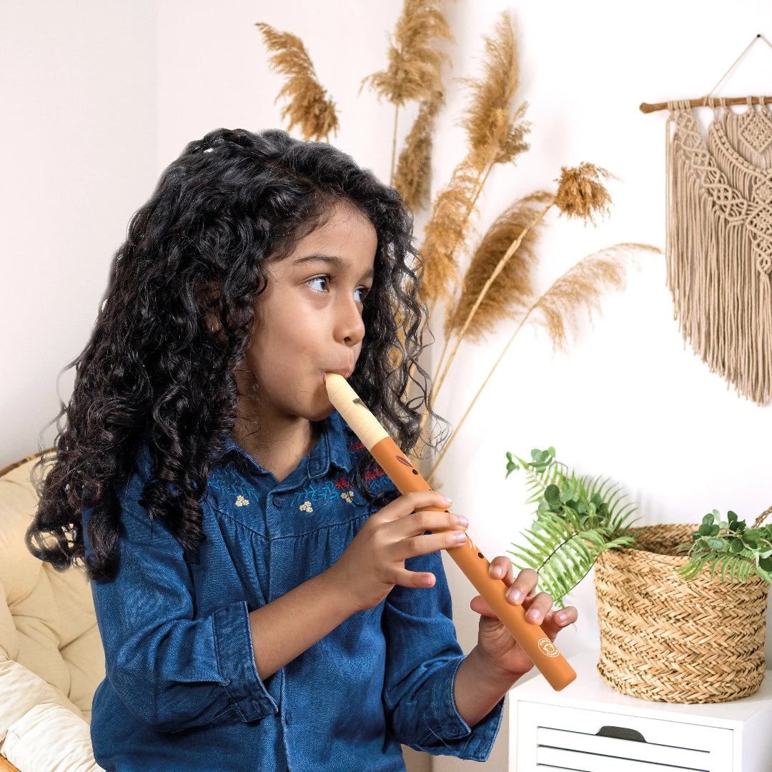 Child playing a wooden recorder in a room with decorative elements