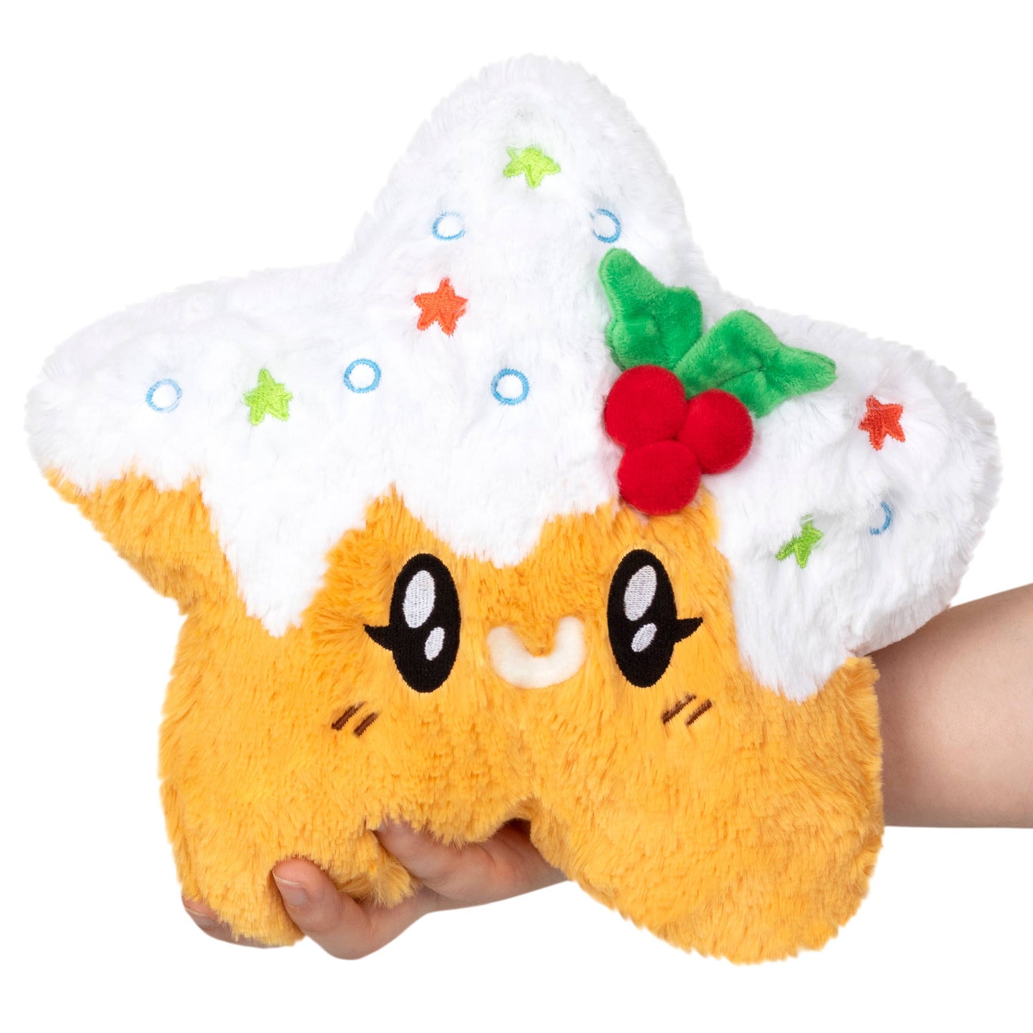 Plush toy resembling a cartoon character with a cake on its head, held by a hand against a white background.