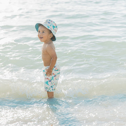 Toddler boy wearing a Coral Reef Reversible Bucket Hat with ocean-inspired prints on both sides, offering soft, breathable comfort and UPF 50+ sun protection for all-day outdoor play.