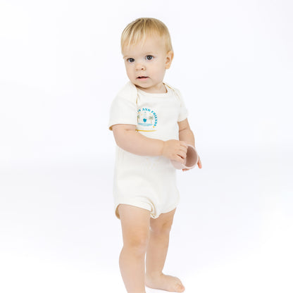 Baby wearing a white bodysuit with a blue graphic and text on a white background
