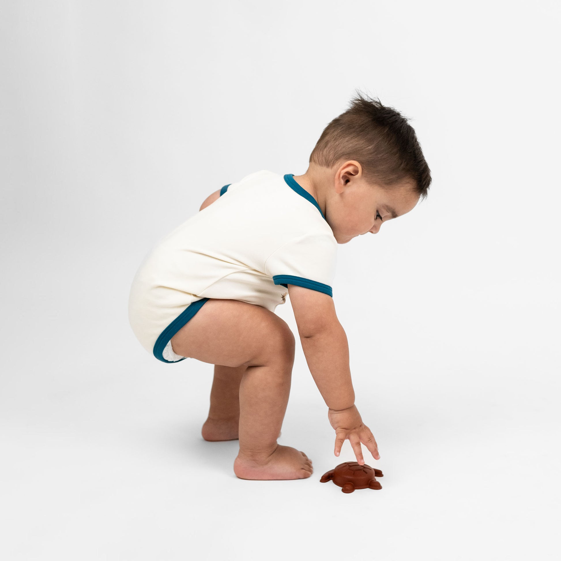 Baby boy wearing our Howdy cotton onesie featuring the word "Howdy" in playful, blue letters, perfect for a western outfit.