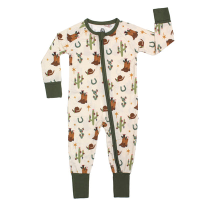 A baby's long-sleeve footless zip-up sleeper with a western-themed print of cacti, cowboy hats, and horses on an off-white background, featuring dark green cuffs, collar, and zipper trim.