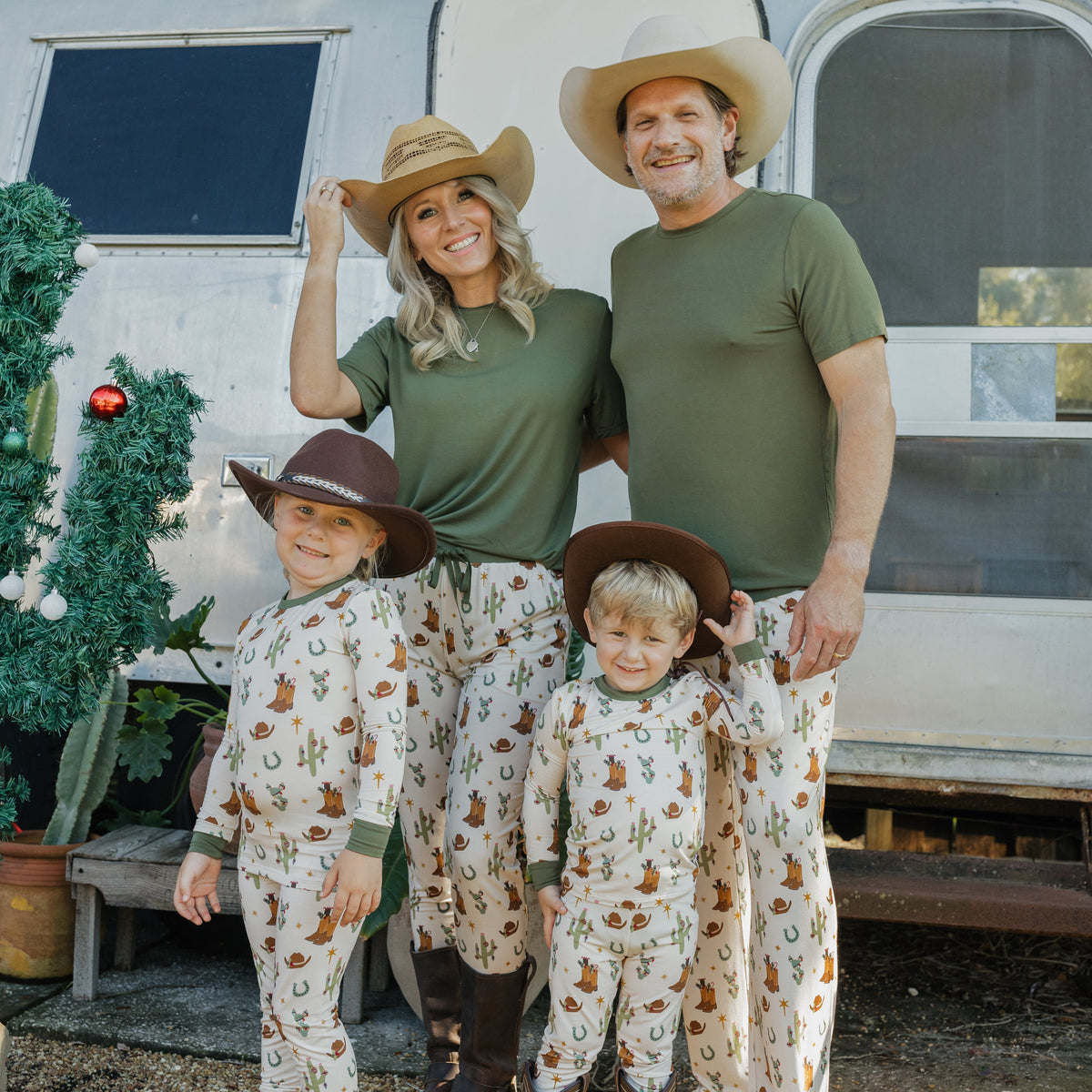 Family wearing coordinating Cowboy Christmas bamboo outfits outdoors, with kids in festive Western holiday pajamas, dad in matching lounge pants, and mom in bamboo joggers.